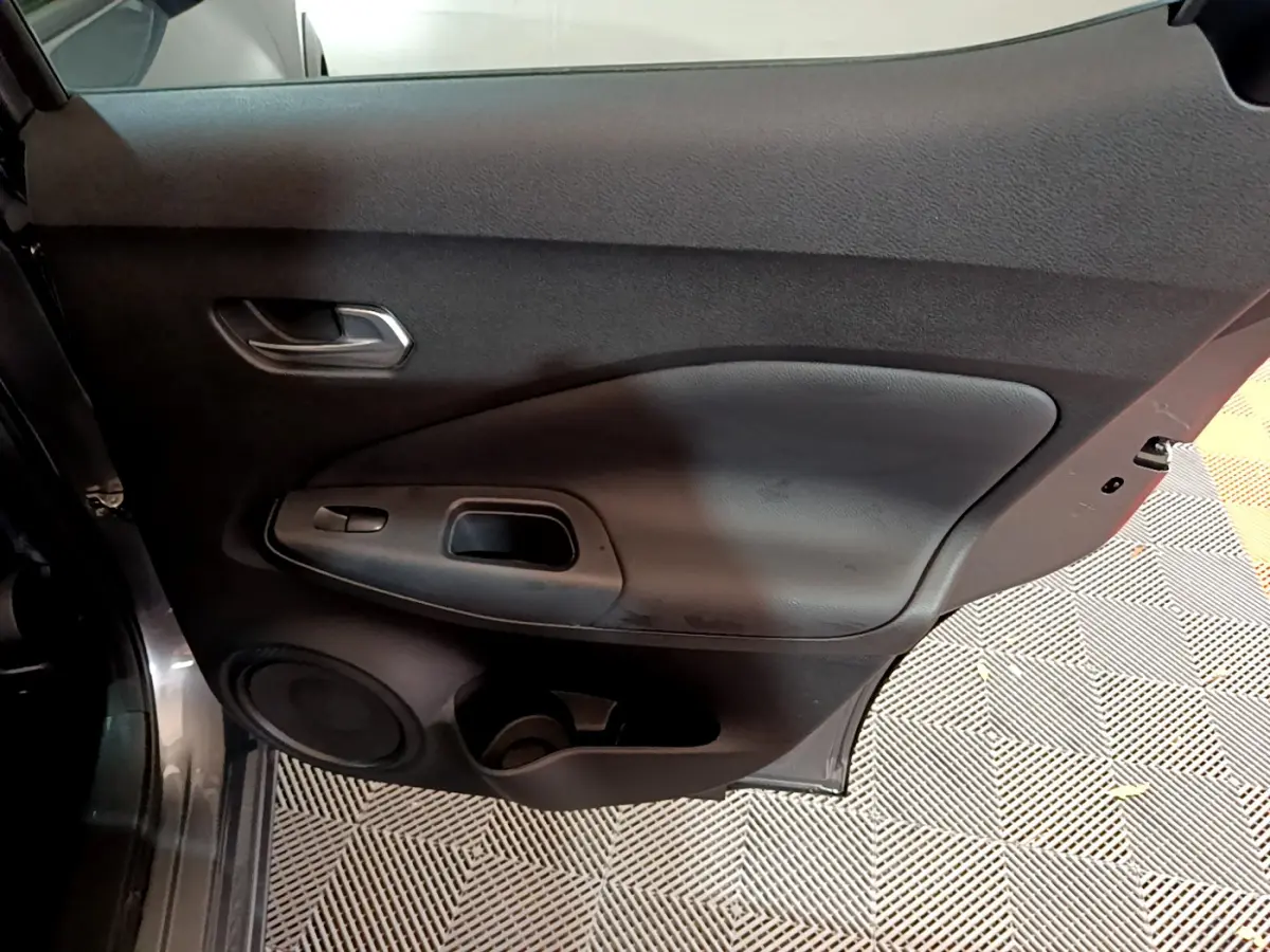 Vue intérieure de la porte arrière gauche gris foncé du Nissan Juke Hybrid 143 Business+ avec haut-parleur intégré.