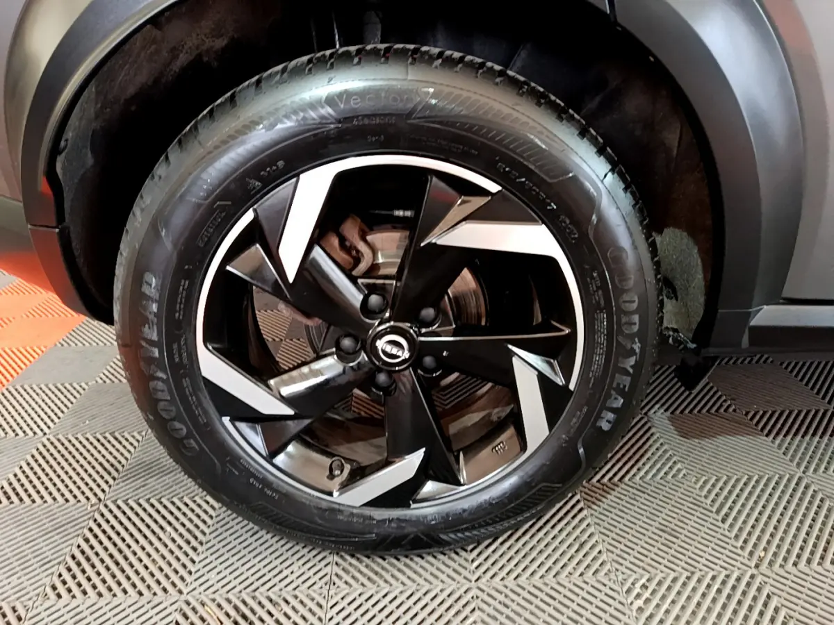 Gros plan sur la roue avant droite du Nissan Juke Hybrid gris foncé, jante noire et argentée au design moderne.