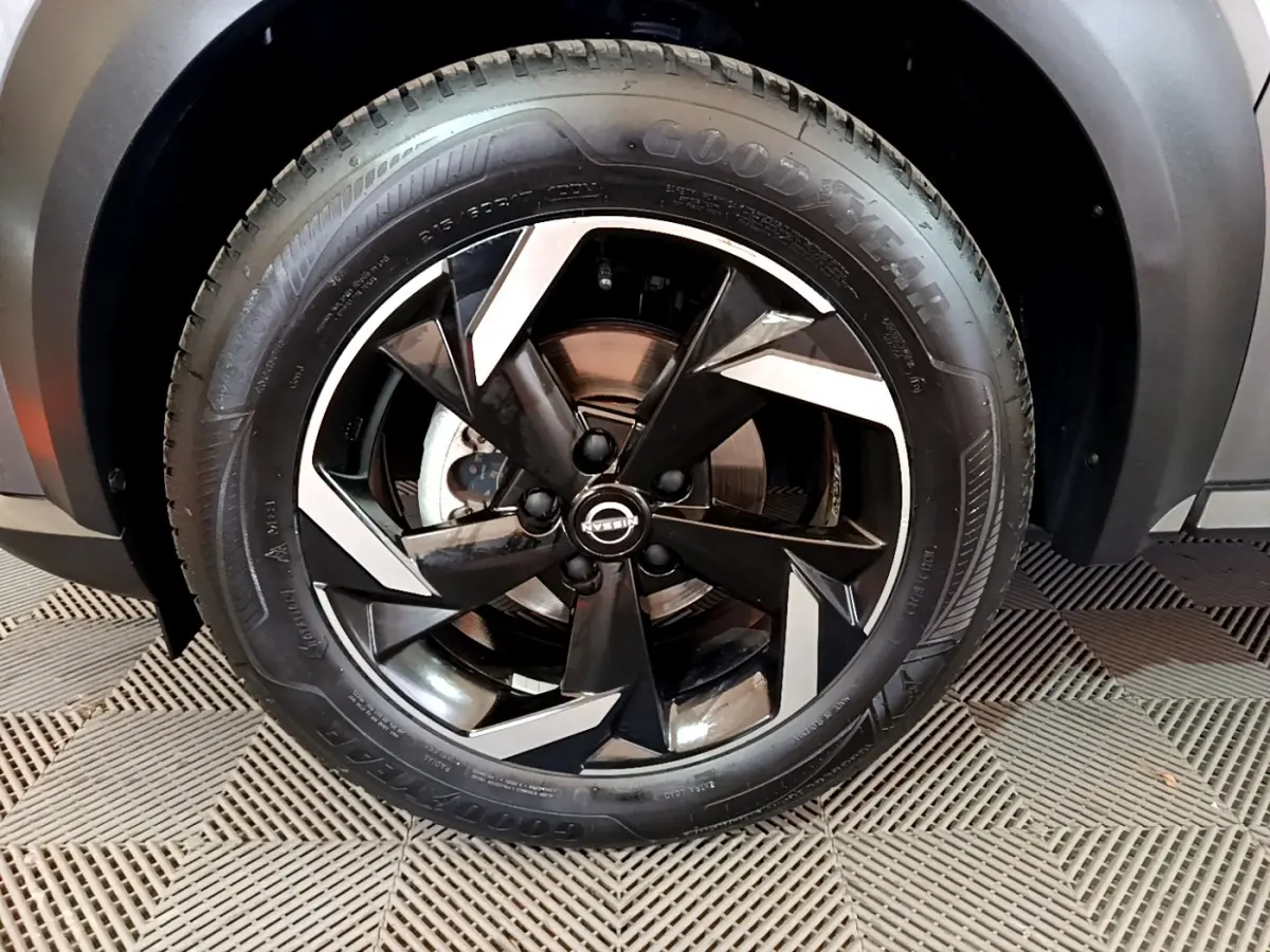Gros plan sur la roue avant droite du Nissan Juke Hybrid 143 Business+ gris foncé avec jante noire et argentée.