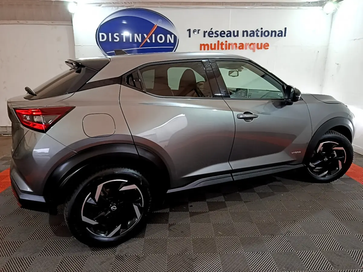 Nissan Juke Hybrid gris foncé vue de profil côté gauche, avec jantes noires et toit contrasté blanc.