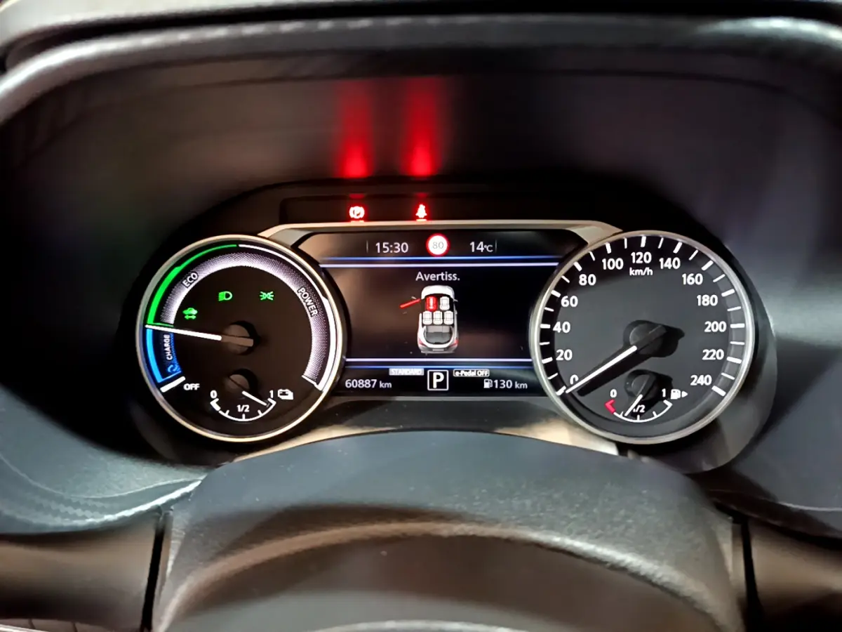 Vue rapprochée du combiné d'instruments numérique et analogique du Nissan Juke Hybrid 143 Business+ affichant alertes et jauges.