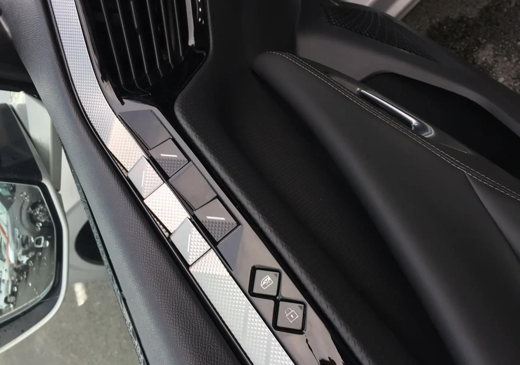 Gros plan sur la commande des vitres côté gauche en cuir noir et inserts argentés dans une DS4 Eph chrystal 2024.