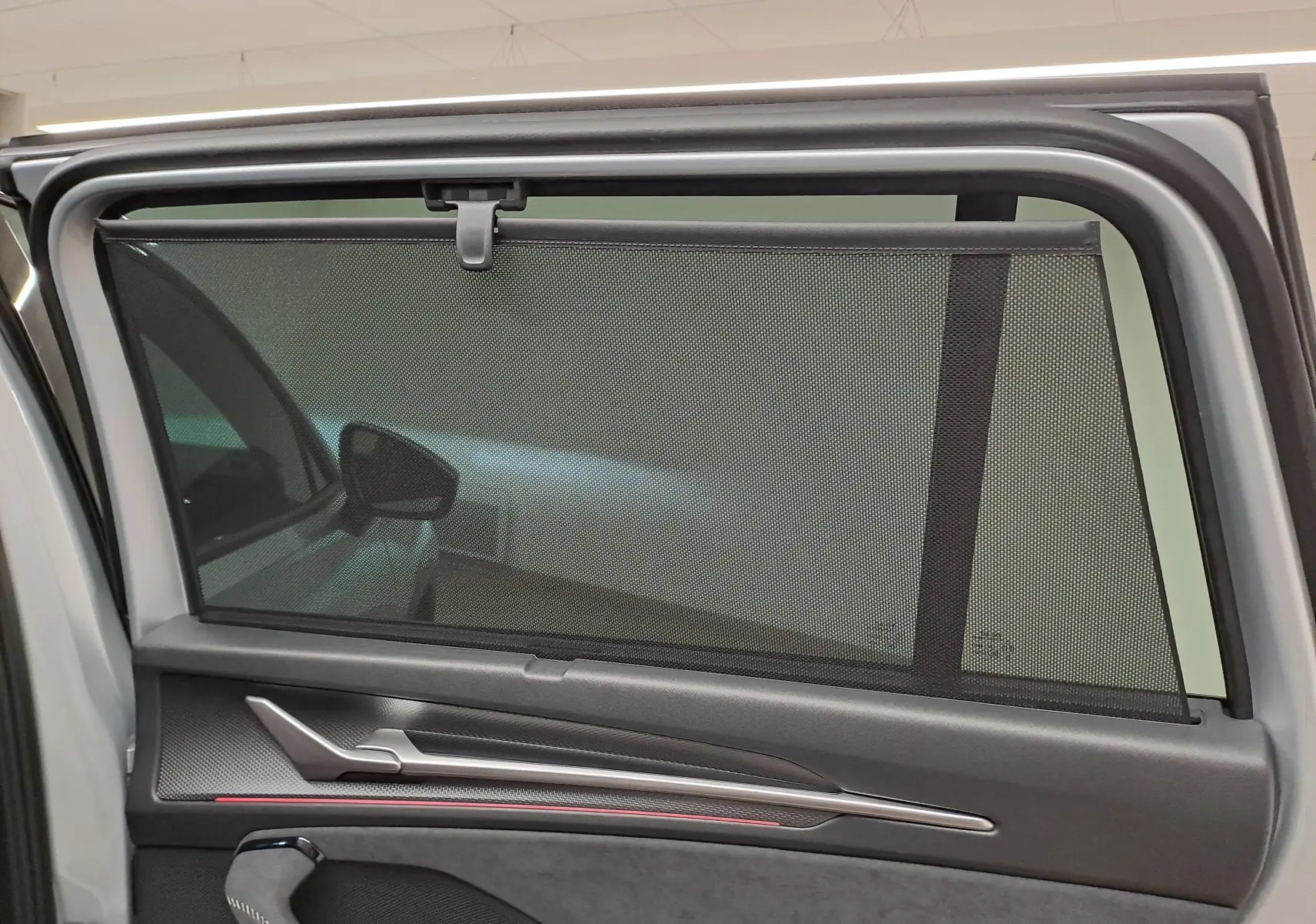 Vue intérieure sur la porte arrière gauche du Skoda Kodiaq gris argent, avec pare-soleil intégré et garniture noire.