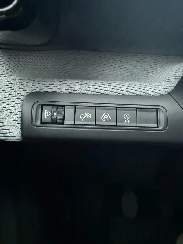 Gros plan sur les commandes de réglage des phares et aides à la conduite dans une Citroën C3 gris 2025.