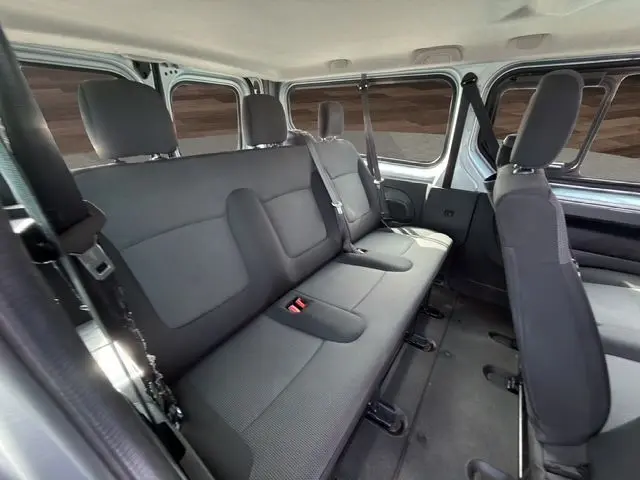 Vue intérieure arrière du Renault Trafic Combi gris platine 2022, montrant les sièges tissu noir et la banquette 9 places.