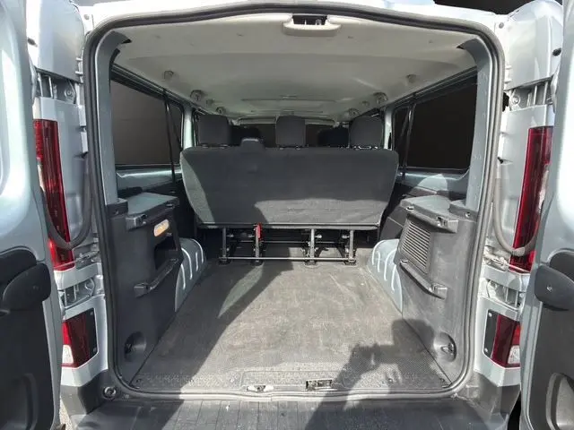 Vue arrière ouverte du Renault Trafic Combi gris platine, montrant l'espace intérieur et la banquette arrière noire.