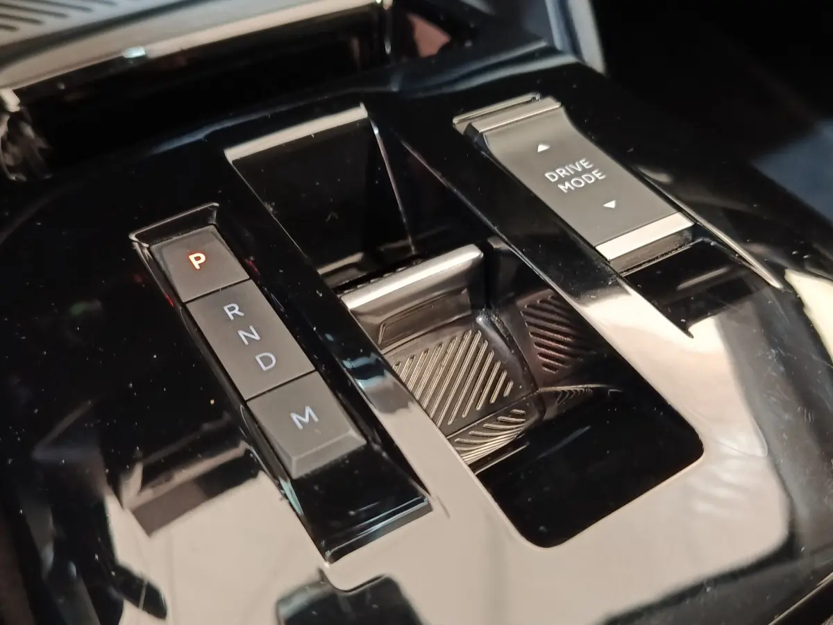 Gros plan sur la console centrale noire brillante de la Citroën C4 2022 avec sélecteur de boîte auto et bouton Drive Mode.