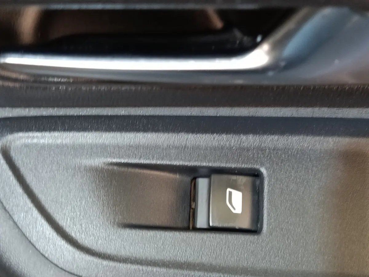 Gros plan sur le bouton de commande de lève-vitre côté conducteur d'une Citroën C4 gris foncé.
