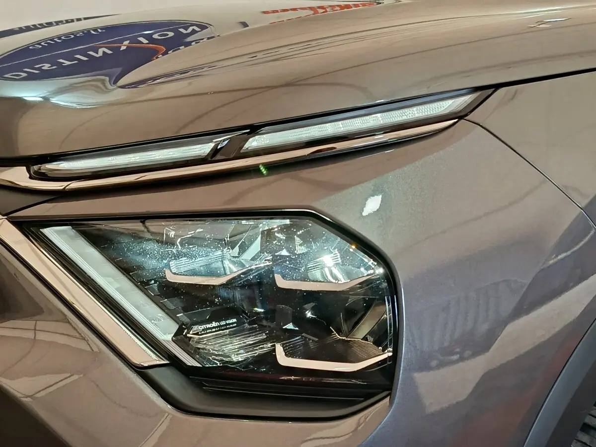 Gros plan sur le phare avant gauche d'une Citroën C4 gris foncé, soulignant son design LED moderne.