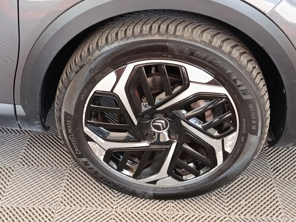 Gros plan sur la roue avant droite d'une Citroën C4 gris foncé, jante alliage bicolore au design moderne.