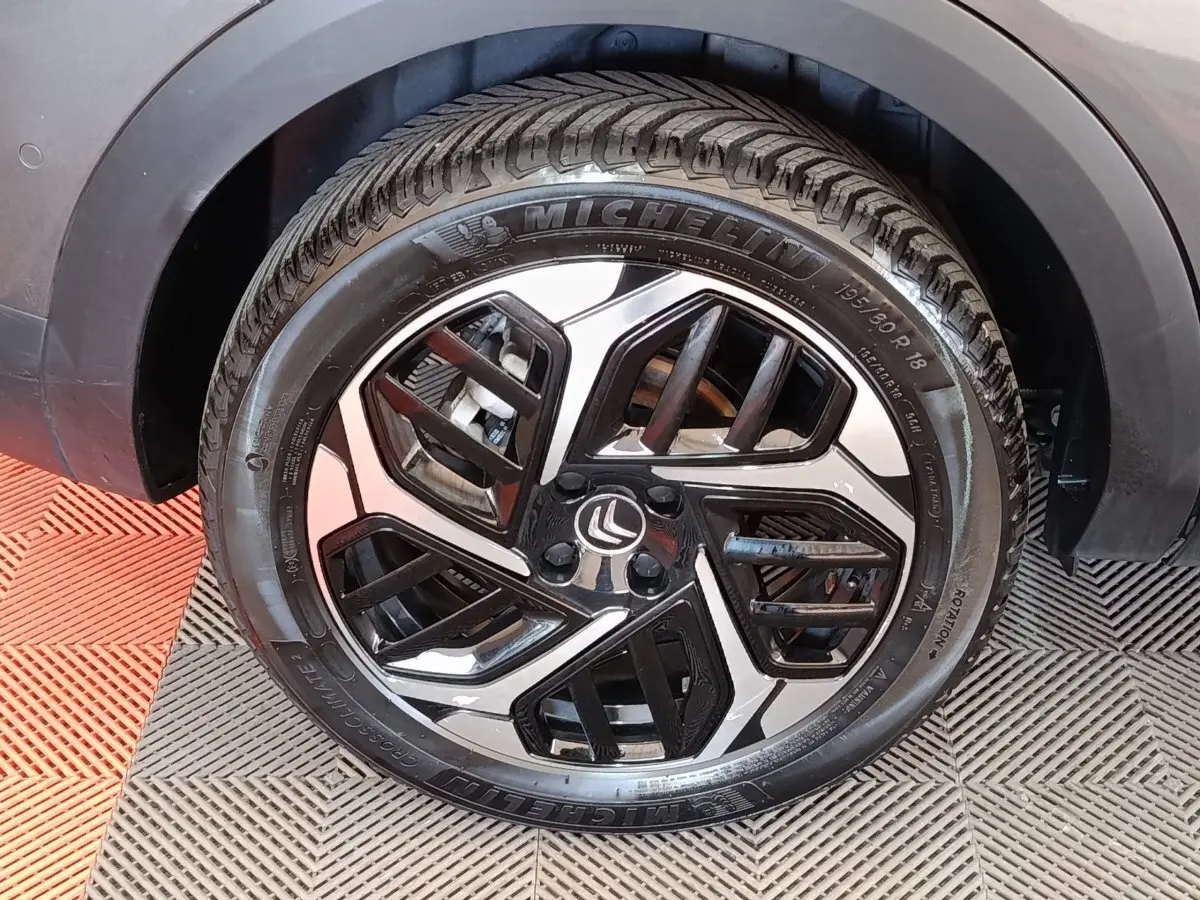 Gros plan sur la roue avant droite gris foncé d'une Citroën C4 2022 avec jante alliage noire et argentée.