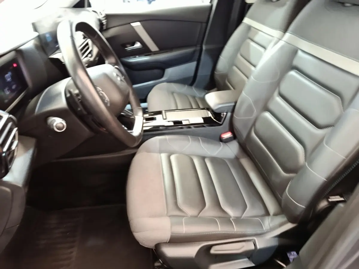 Vue intérieure côté conducteur de la Citroën C4 2022, sièges gris cuir et tableau de bord avec volant multifonctions.