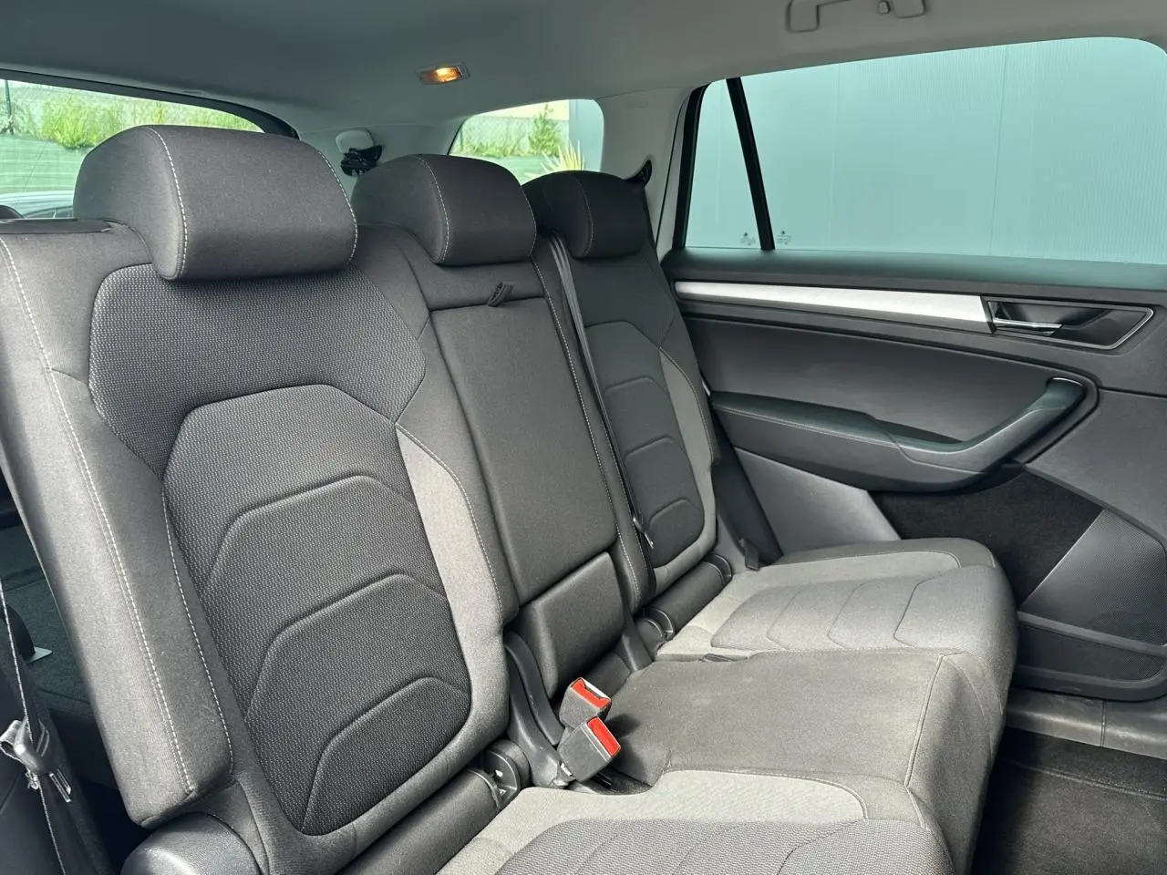 Vue intérieure côté droit des sièges arrière noirs du Skoda Kodiaq blanc Glacier 2024 avec habillage de porte sombre.