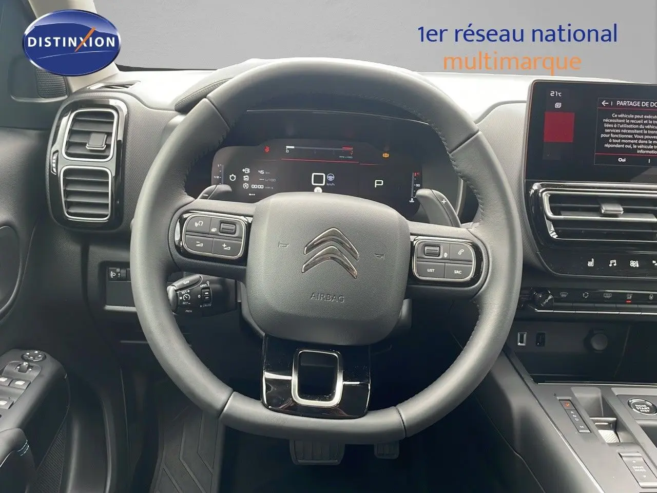 Vue intérieure centrée sur le volant noir du Citroën C5 Aircross 2025 avec tableau de bord digital et écran tactile.