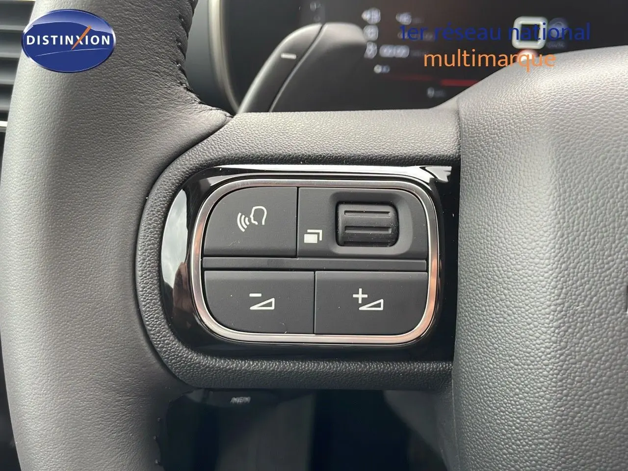 Gros plan sur les commandes gauche du volant du Citroën C5 Aircross 2025, cuir noir et boutons de réglage audio.