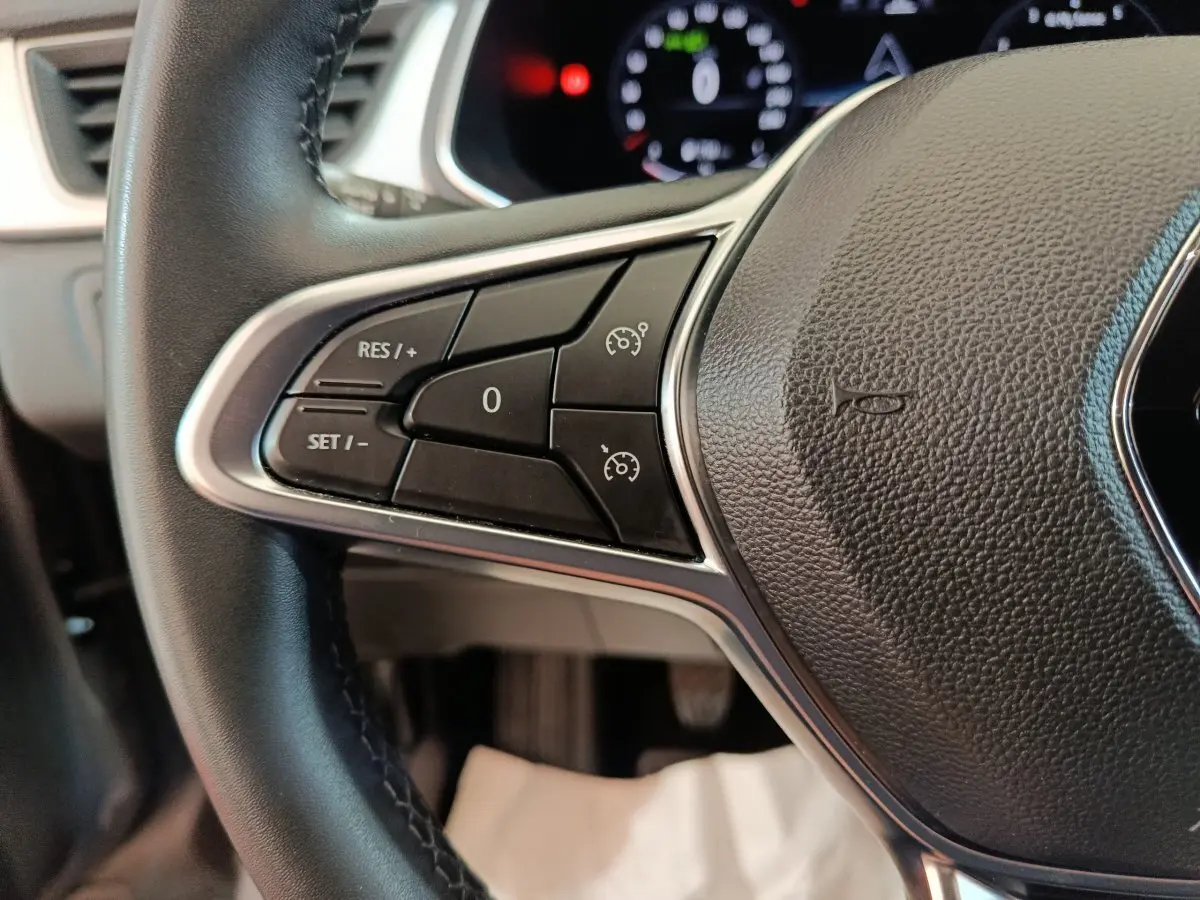 Gros plan sur les commandes du volant noir du Renault Captur Techno TCe 90 2024, affichage numérique en arrière-plan.