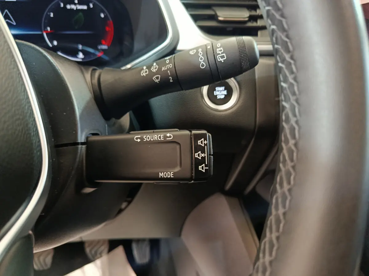 Gros plan sur la commande multifonctions côté gauche du volant du Renault Captur gris foncé avec bouton démarrage visible.