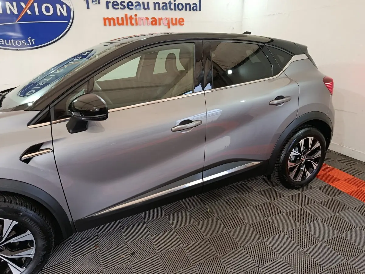 Profil côté gauche d'un Renault Captur gris foncé 2024 avec rétroviseurs noirs et jantes alliage bicolores.