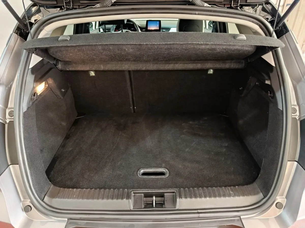 Coffre ouvert vu de l'arrière d'un Renault Captur gris foncé, montrant un espace de chargement propre et spacieux.