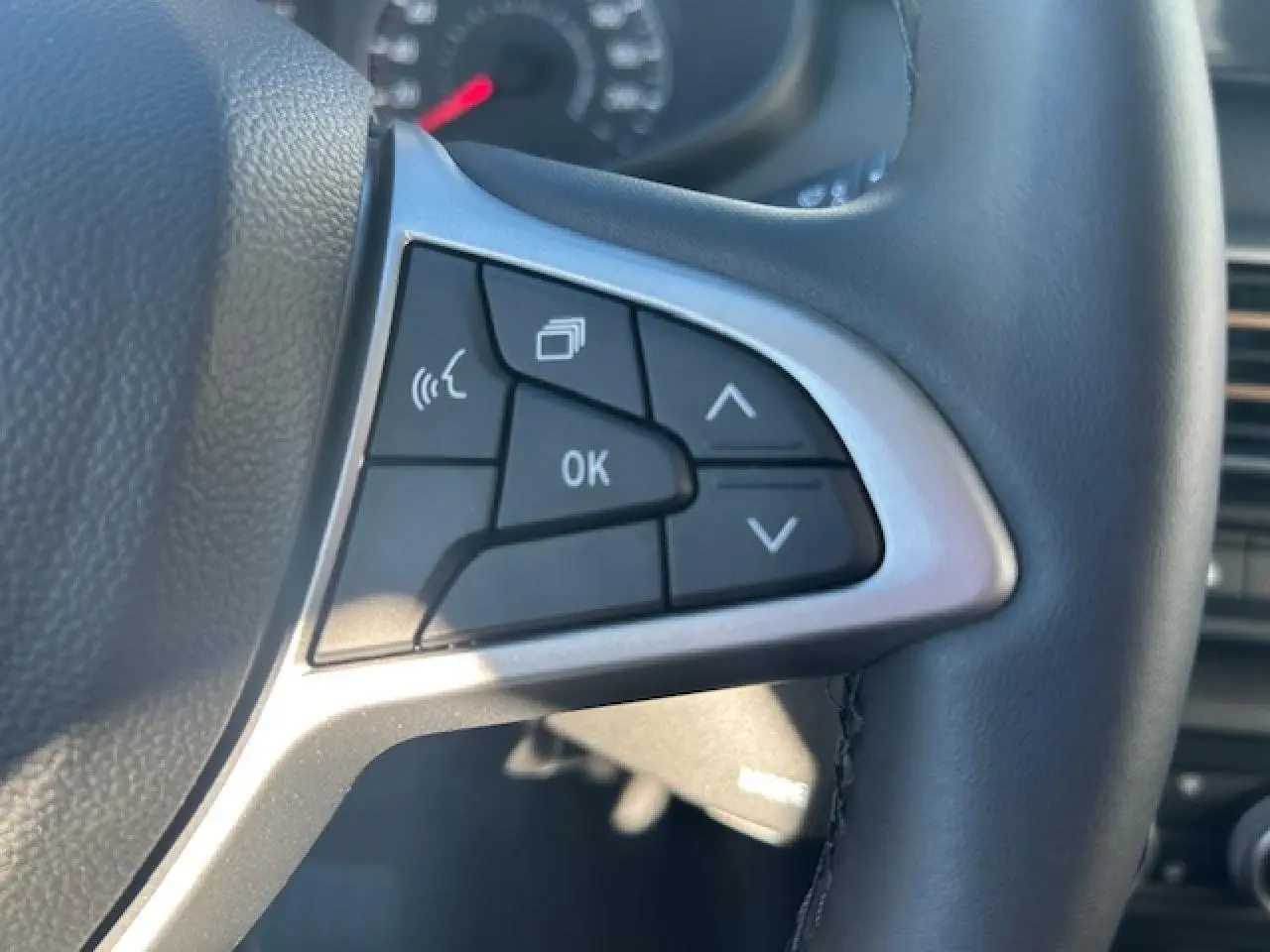 Gros plan sur les commandes gauche du volant noir de la Dacia Sandero Stepway 2025, avec finition argentée.