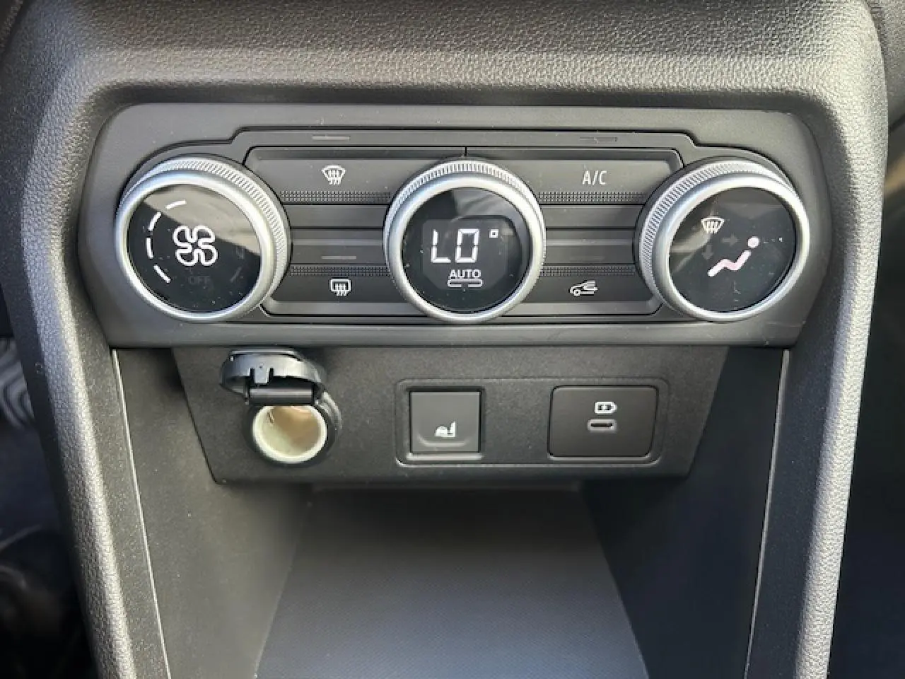 Gros plan sur la console centrale noire du Dacia Sandero Stepway 2025, montrant les commandes de climatisation automatique.