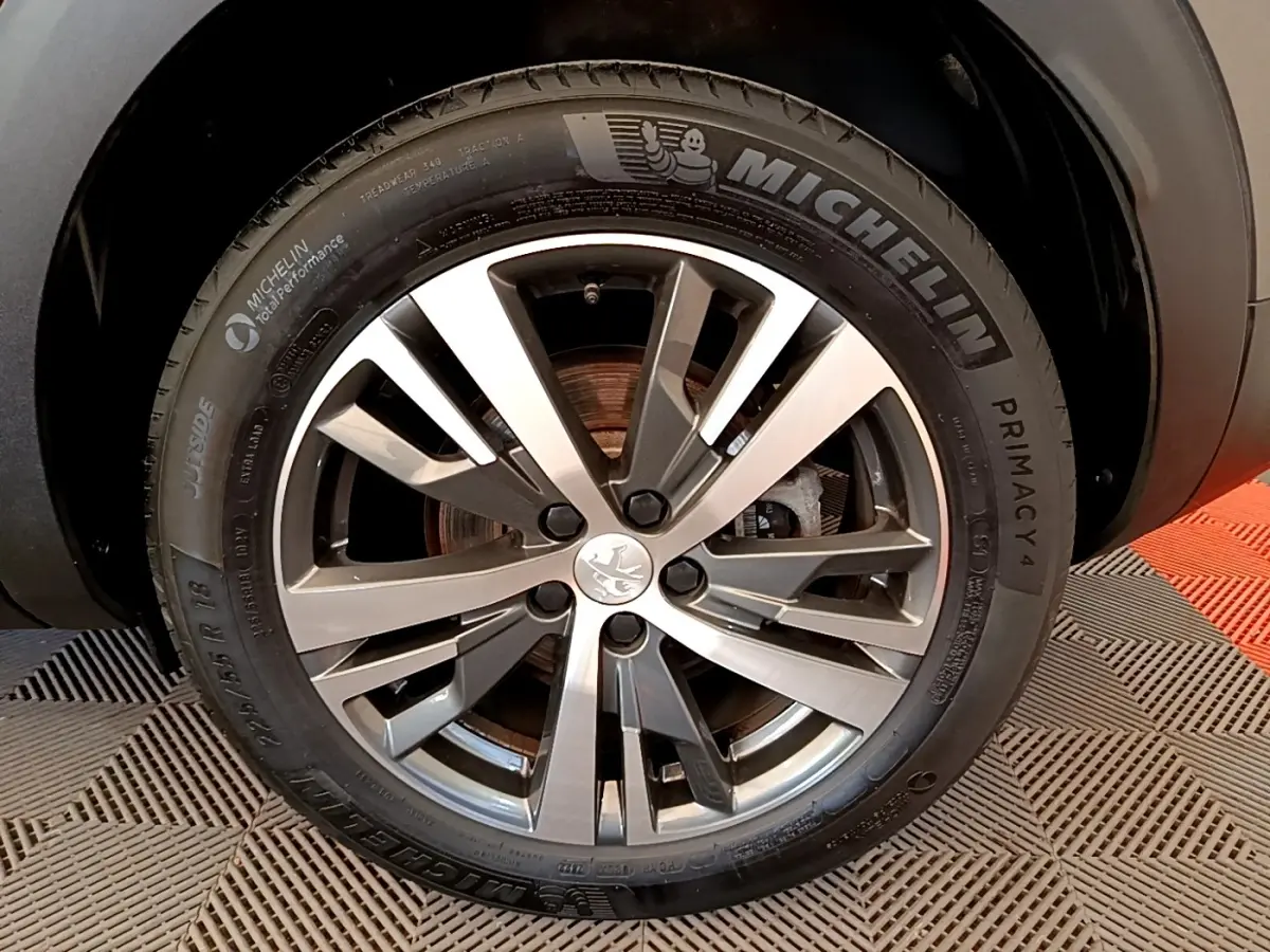 Gros plan sur la roue avant droite d’un Peugeot 3008 gris foncé, jante alliage et pneu Michelin Primacy 4.