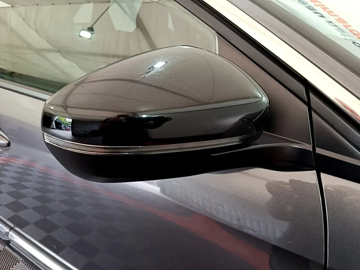 Rétroviseur côté gauche noir brillant sur Peugeot 3008 gris foncé, vue rapprochée en intérieur.