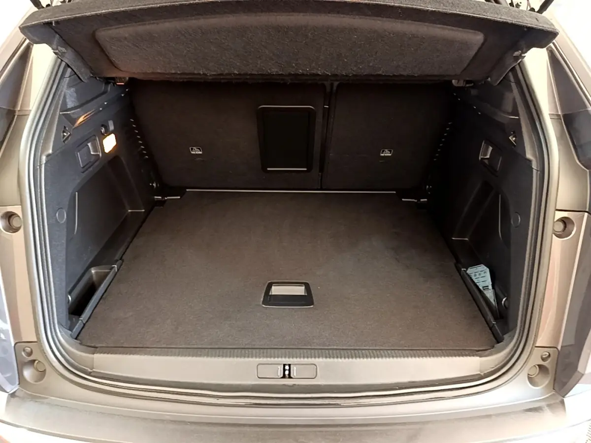 Coffre ouvert vu de l'arrière d'un Peugeot 3008 gris foncé, montrant un espace de chargement propre et spacieux.
