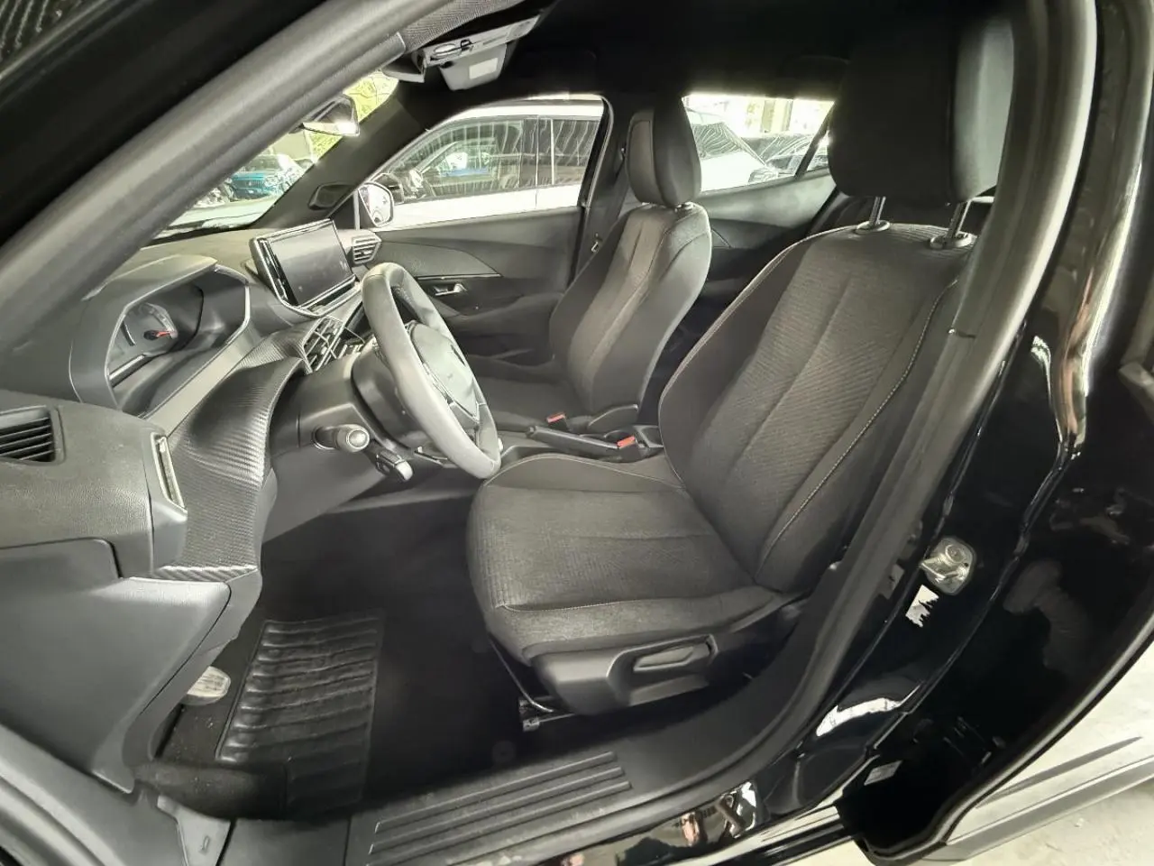 Intérieur avant droit du Peugeot 2008 noir perla 2025, montrant sièges tissu et tableau de bord moderne avec écran tactile.