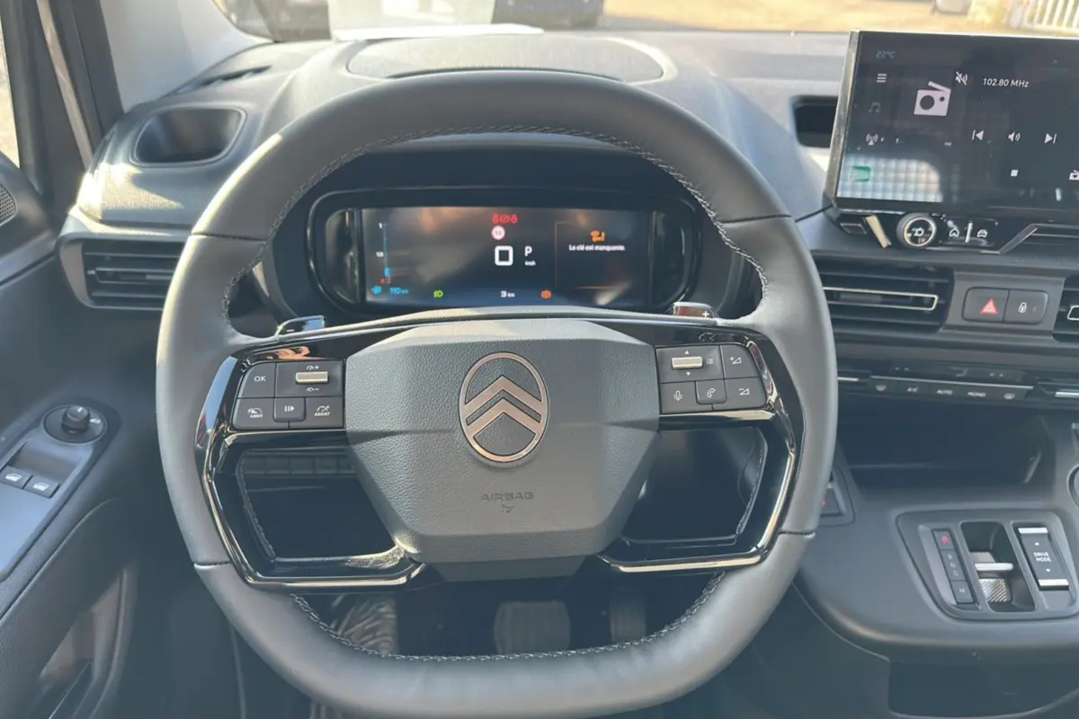 Vue intérieure centrée sur le volant noir du Citroën Berlingo 2025 avec tableau de bord digital et écran tactile.