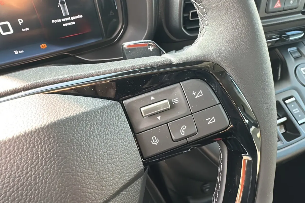 Vue rapprochée des commandes au volant du Citroën Berlingo 2025, finition BlueHDi 130 EAT8, avec tableau de bord numérique.