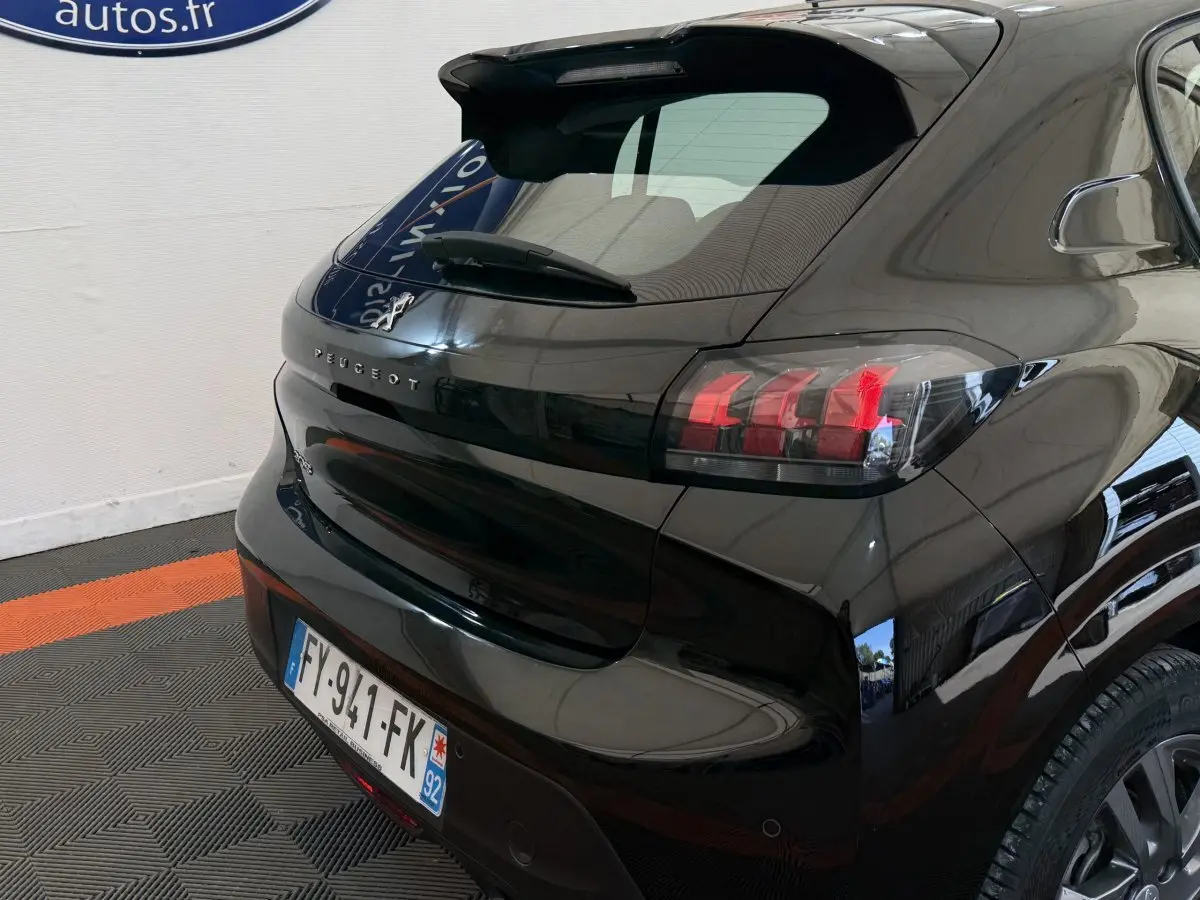 Vue 3/4 arrière droite d'une Peugeot 208 noire avec feux arrière LED et lunette arrière surélevée.