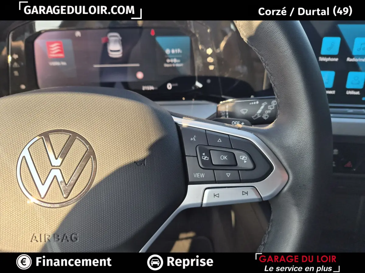 Gros plan sur le volant noir de la Volkswagen Golf 2023 avec commandes multifonctions et logo VW central.