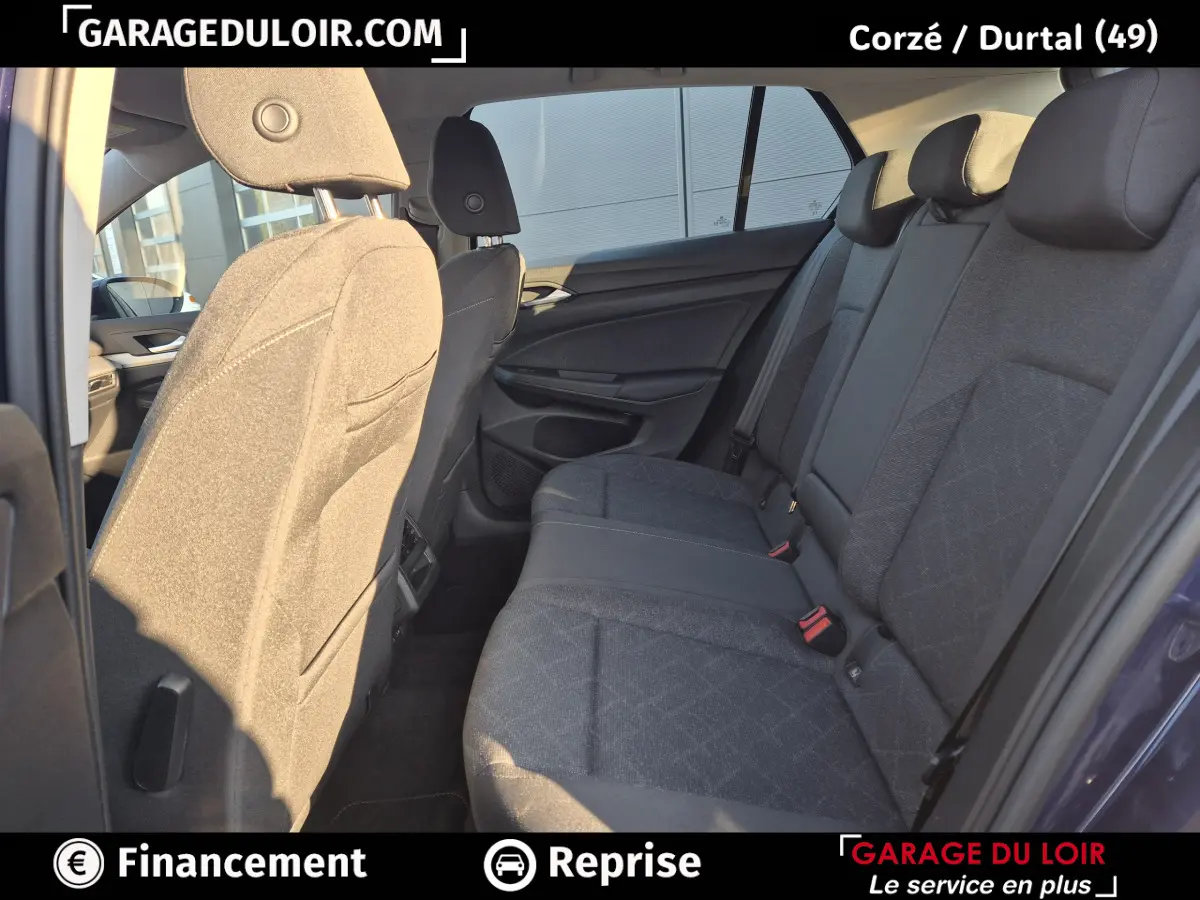 Vue intérieure côté droit des sièges arrière gris foncé d'une Volkswagen Golf 2023 bleue, avec appuie-têtes et ceintures visibles.