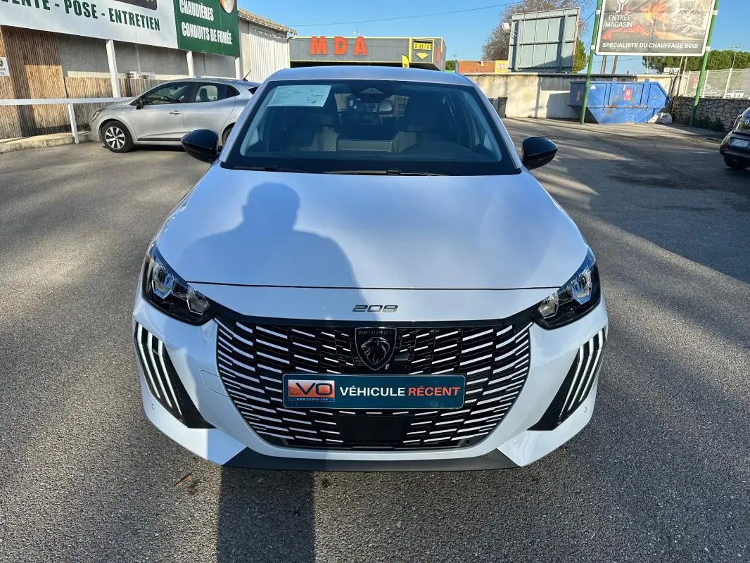 Vue avant d’une Peugeot 208 Hybrid 110 e-DCS6 Allure blanche avec calandre noire et feux LED distinctifs.