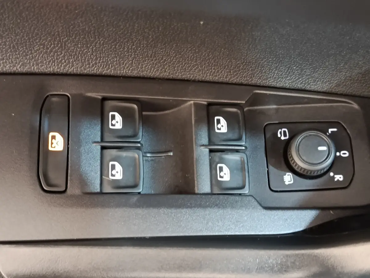 Gros plan sur les commandes des vitres et rétroviseurs côté gauche d’un Volkswagen Taigo gris foncé 2023.