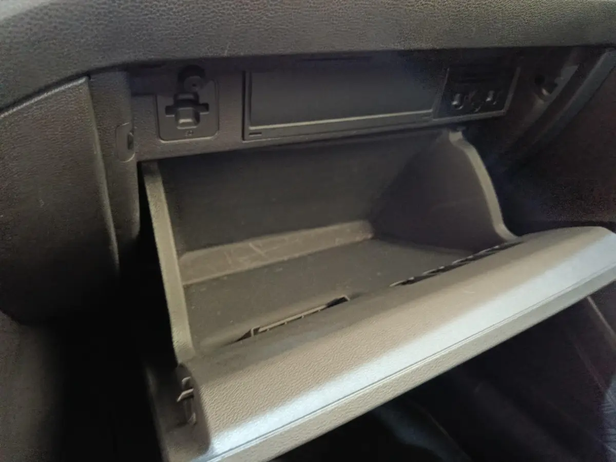 Gros plan sur la boîte à gants ouverte côté passager du Volkswagen Taigo gris foncé, intérieur noir.