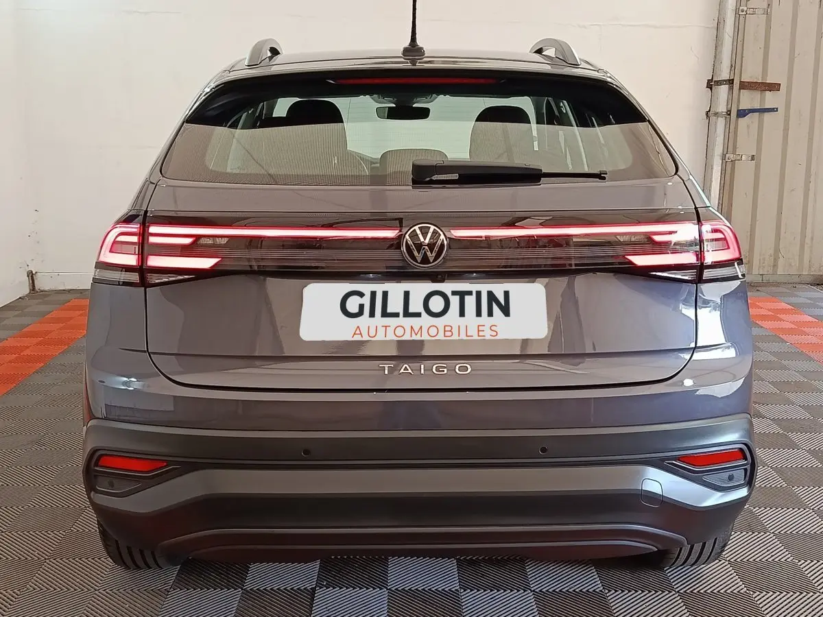 Vue arrière d'un Volkswagen Taigo gris foncé 2023 avec feux arrière LED allumés et logo central visible.