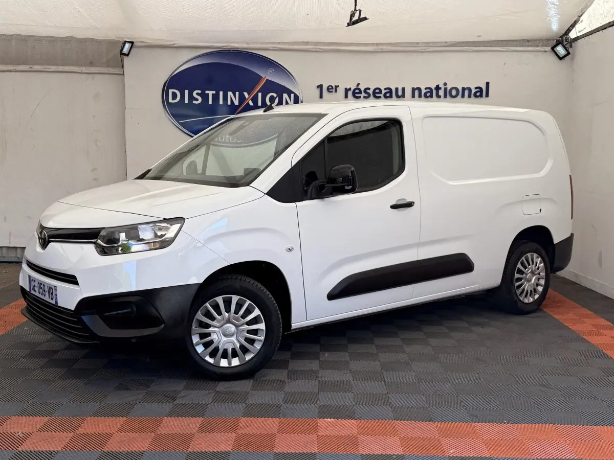 Vue 3/4 avant droit d'un Toyota Proace City blanc, fourgon utilitaire avec protections noires sur les bas de caisse et pare-chocs.