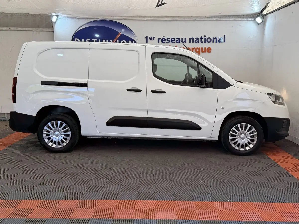 Vue de profil côté droit d'un Toyota Proace City blanc, fourgon utilitaire avec porte latérale coulissante et jantes acier.