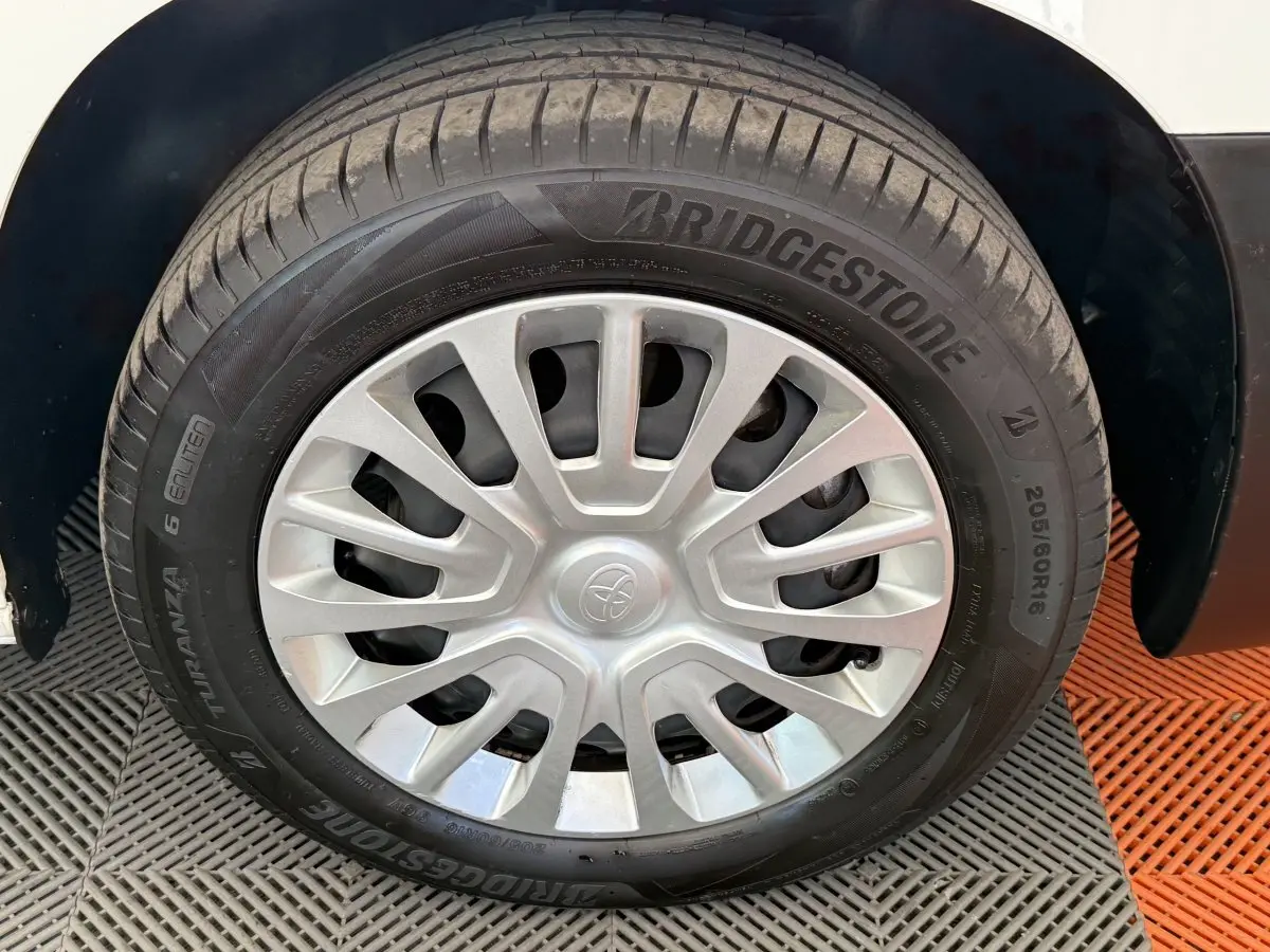 Gros plan sur la roue avant droite d’un Toyota Proace City blanc avec jante en acier et enjoliveur gris.