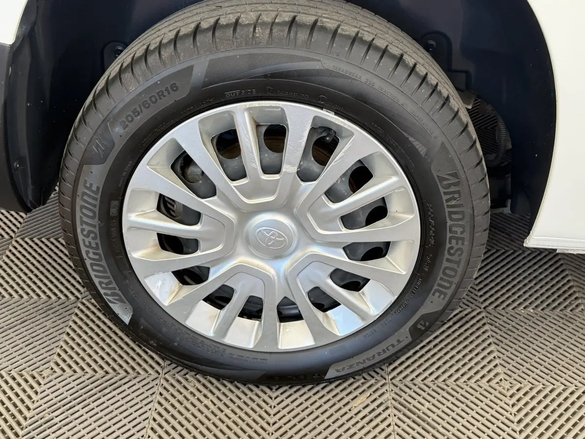 Gros plan sur la roue avant droite d’un Toyota Proace City blanc, jante acier avec enjoliveur gris.