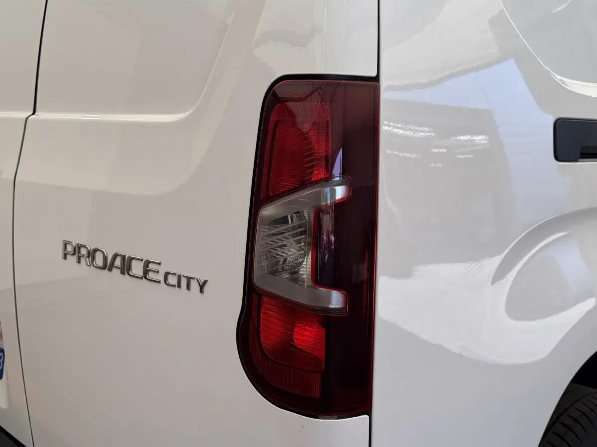 Gros plan sur le feu arrière droit et le logo PROACE CITY d’un utilitaire Toyota blanc.