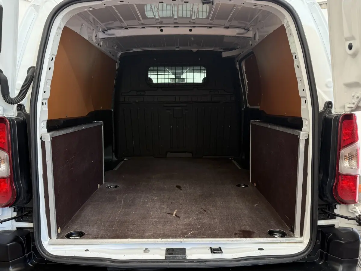 Vue arrière du coffre blanc du Toyota Proace City 1.5 LONG 130 D-4D Business, montrant l’espace de chargement vide et cloison pleine.