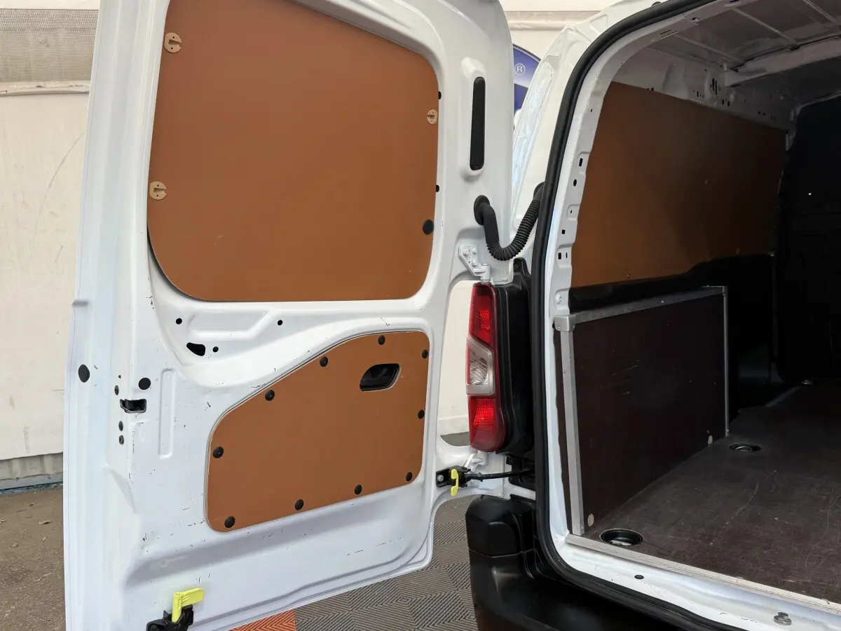 Vue arrière ouverte du Toyota Proace City blanc, montrant l'intérieur utilitaire avec panneaux de protection marron.