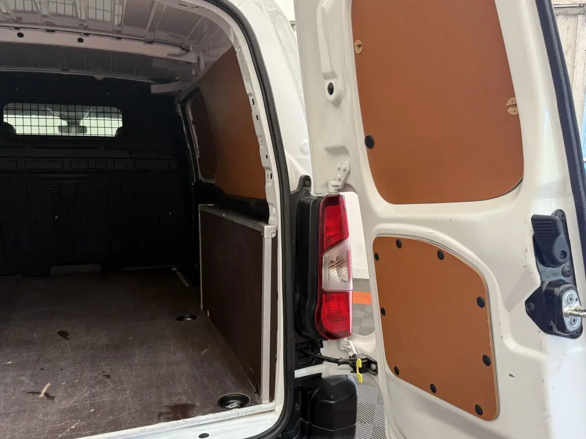 Vue arrière ouverte du Toyota Proace City blanc, montrant l'intérieur de la zone de chargement avec panneaux de protection marron.