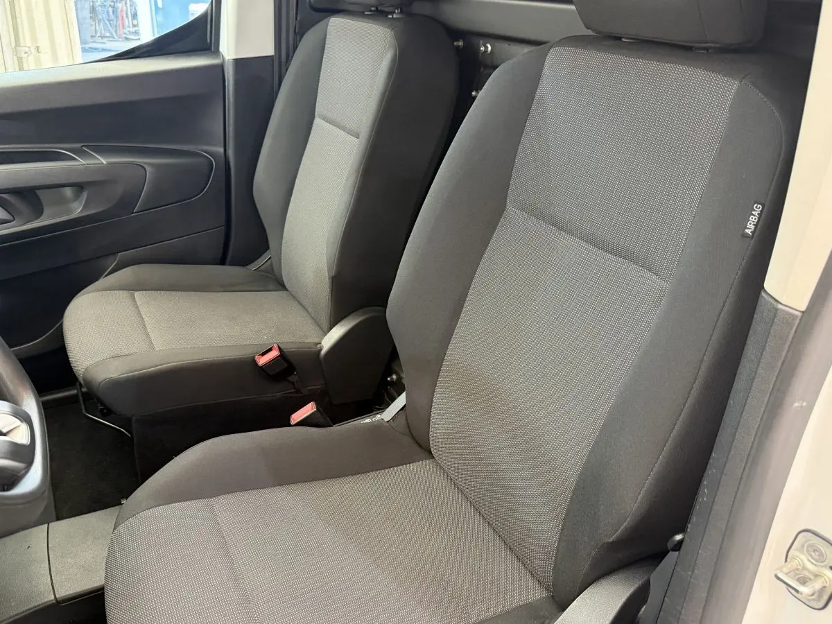 Vue intérieure rapprochée des sièges avant gris foncé du Toyota Proace City 1.5 Long 130 D-4D Business, porte ouverte côté droit.