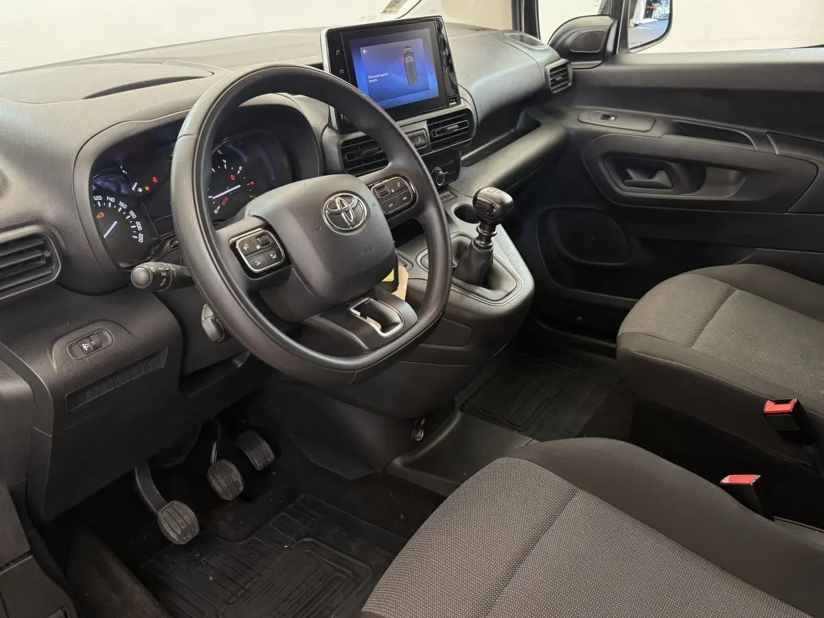 Vue intérieure côté conducteur du Toyota Proace City 2022, volant multifonctions, écran tactile central et boîte manuelle noire.