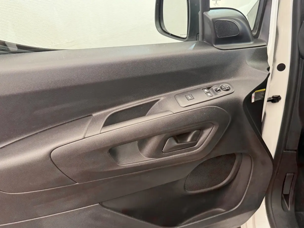 Vue rapprochée de la porte avant droite noire du Toyota Proace City blanc, avec commandes électriques des vitres et rétroviseurs.