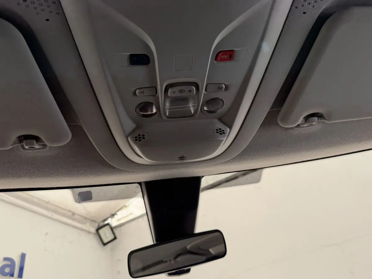 Vue intérieure du toit avec commandes d'éclairage, bouton SOS rouge et rétroviseur central du Toyota Proace City blanc.